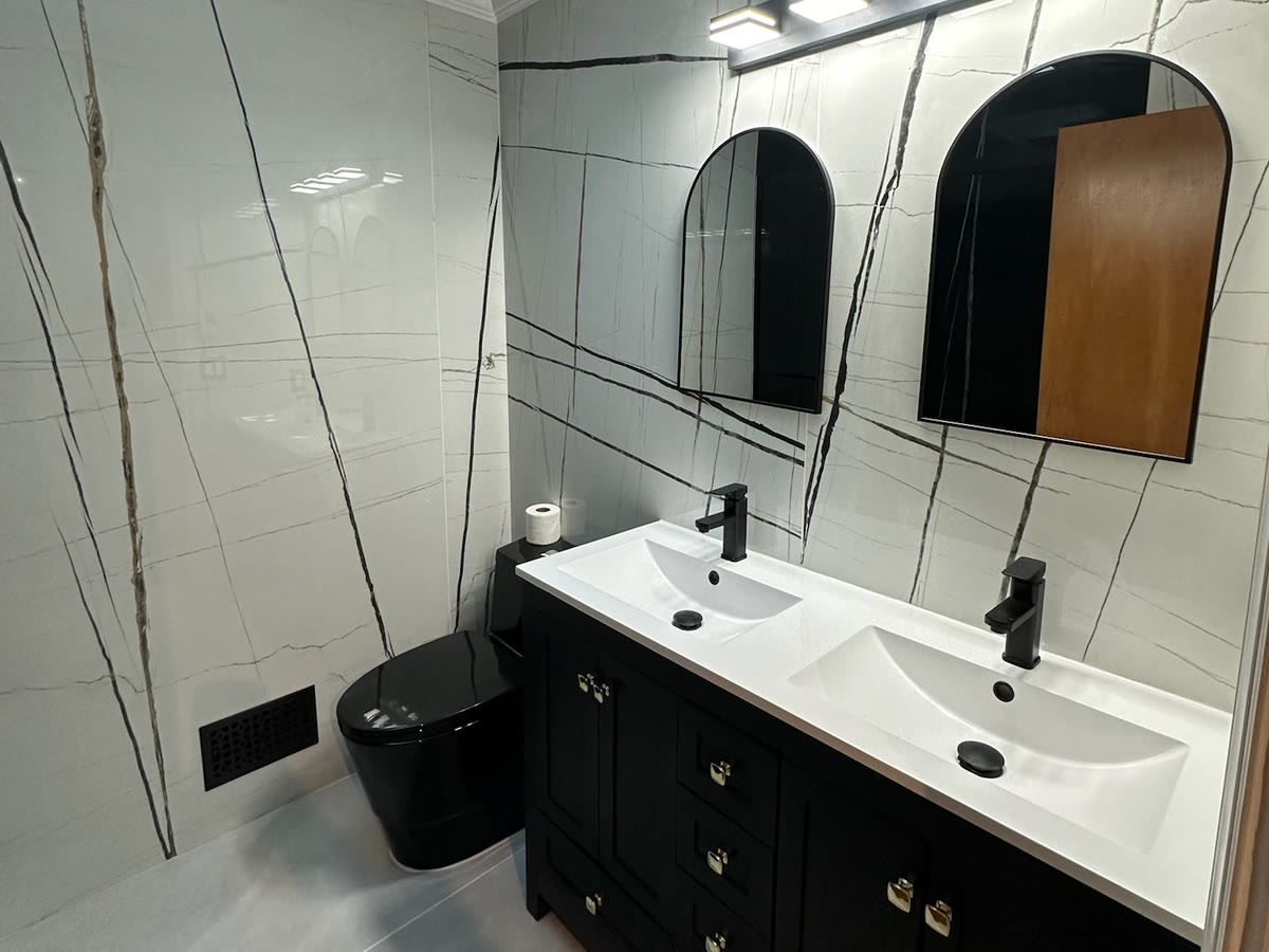 Real ARCED bathroom — double vanity, black cabinetry, marble-look porcelain walls, matte-black fixtures