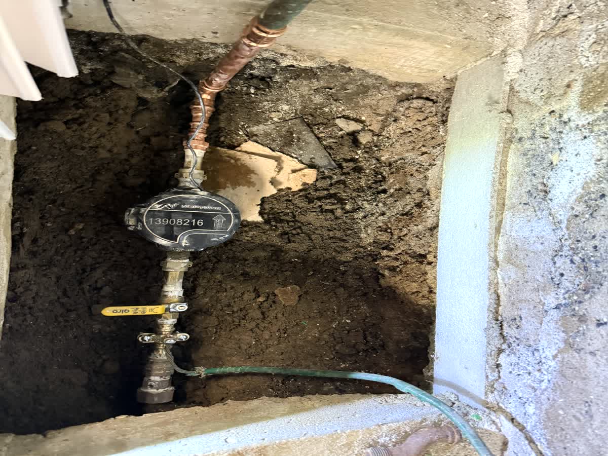 Real ARCED plumbing — copper water service line to the meter and shutoff valve, trenched at the foundation